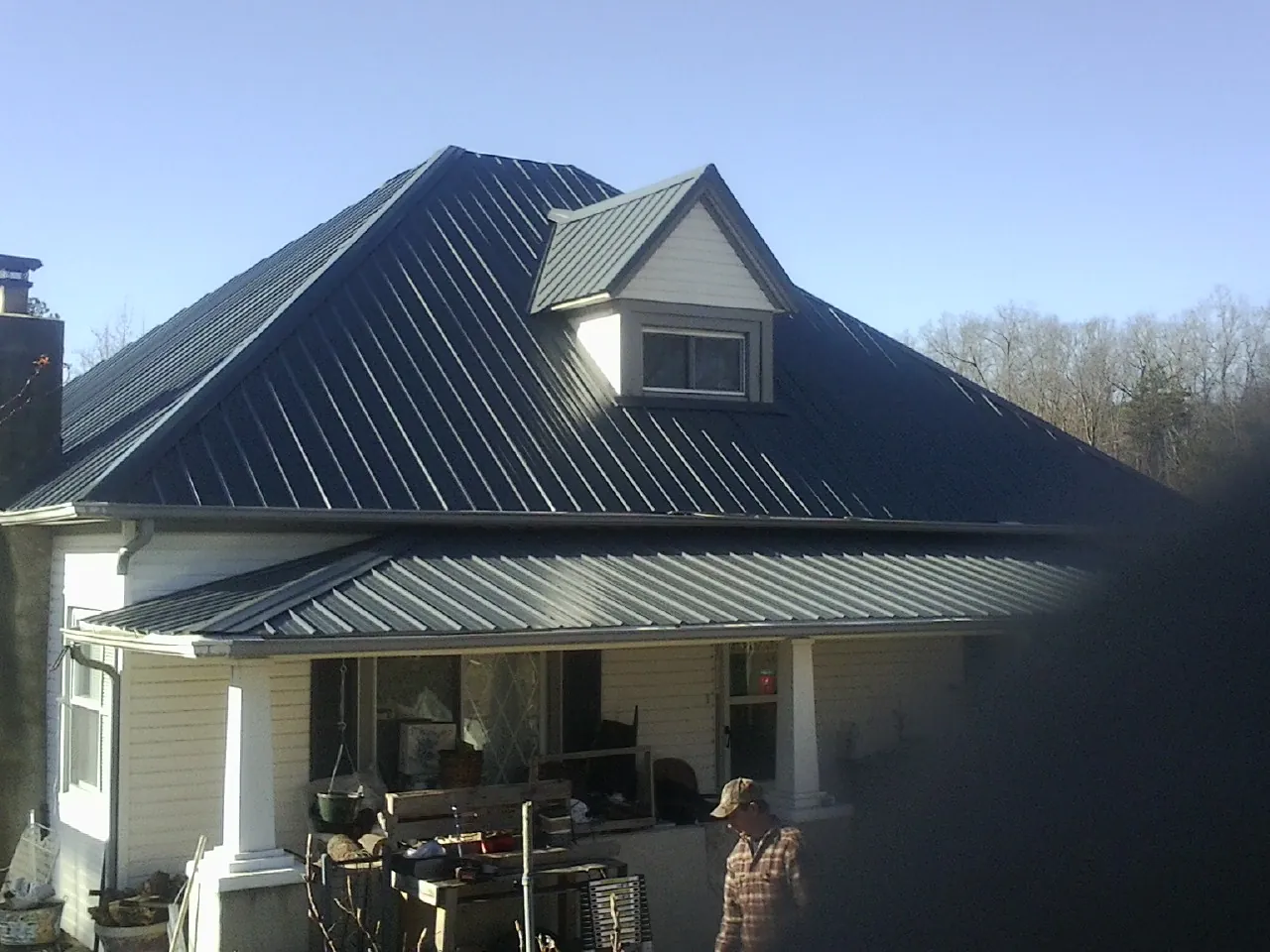 Dark blue standing seam metal roof with a dormer above a front porch in Ford Cliff