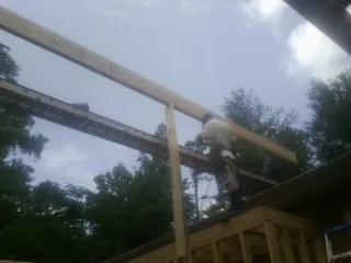 Carpenter setting a ridge beam over a new addition frame — Ice Dam Removal by Roofing Brothers in Ford Cliff