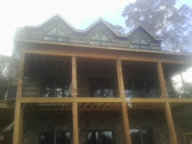 Dormers and porch framing on a large log home under construction — Roof Coating work by our crew in Ford Cliff