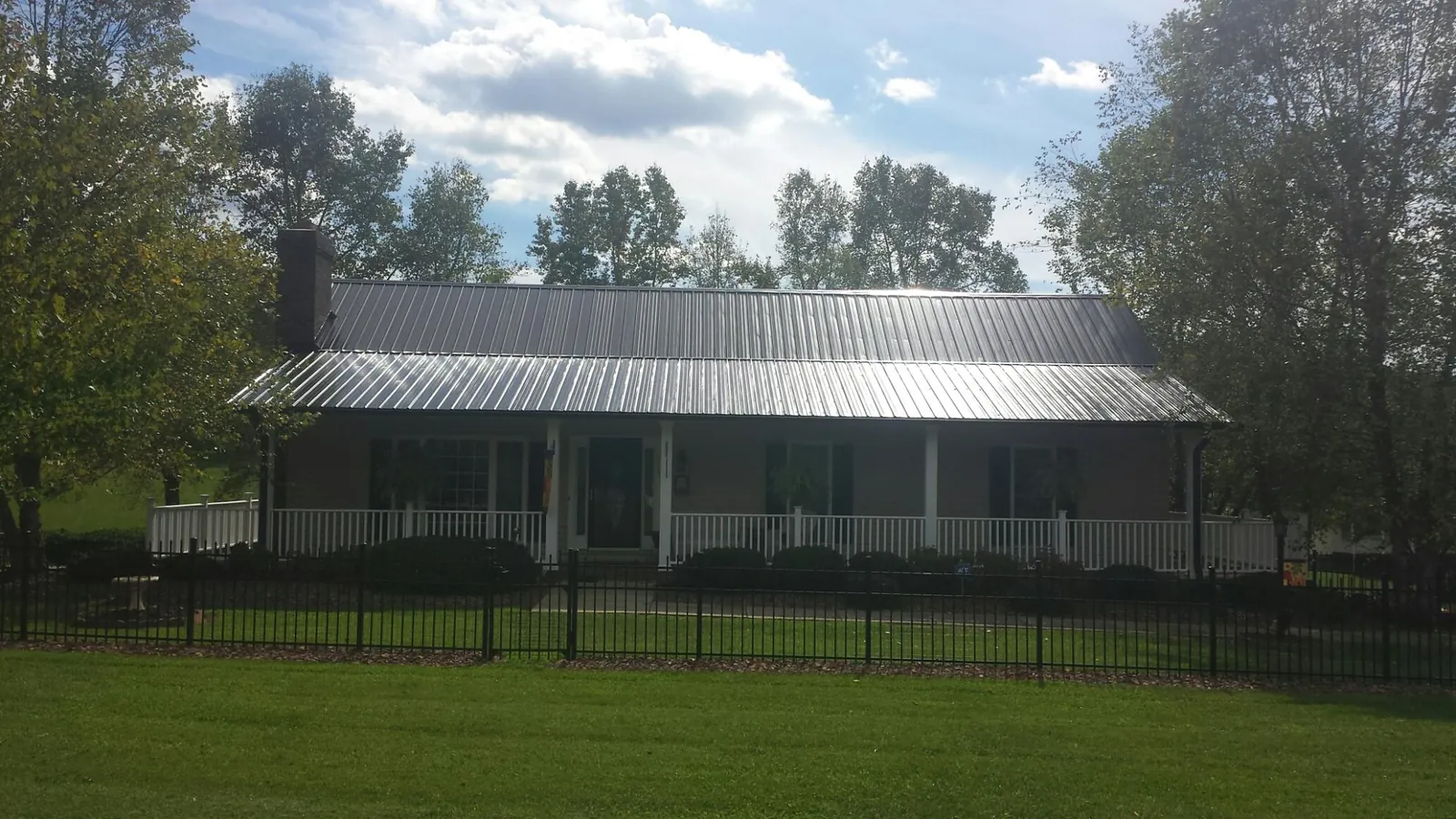 Gray metal roof on a brick ranch with a full width front porch — Gutter Guard Installation work by our crew in Ford Cliff