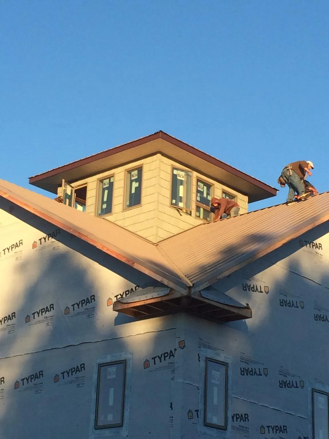 Roofers working around a rooftop cupola on a new metal roof at sunset — Roof Waterproofing in Ford Cliff by Roofing Brothers